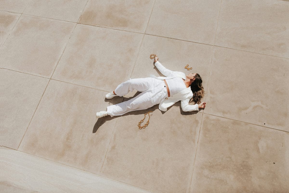 Ragazza vestita di bianco stesa e circondata da gioielli tra i quali Trilogy &Eacute;clat - set di anelli in acciaio inossidabile, uno dei nostri gioielli online
